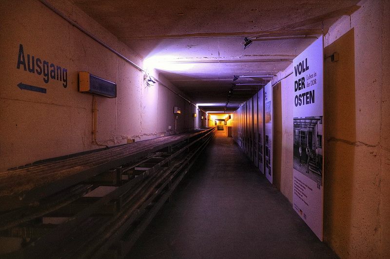 Galerietunnel mit Ausgangsschild und Ausstellungstafeln in der Dämmerung